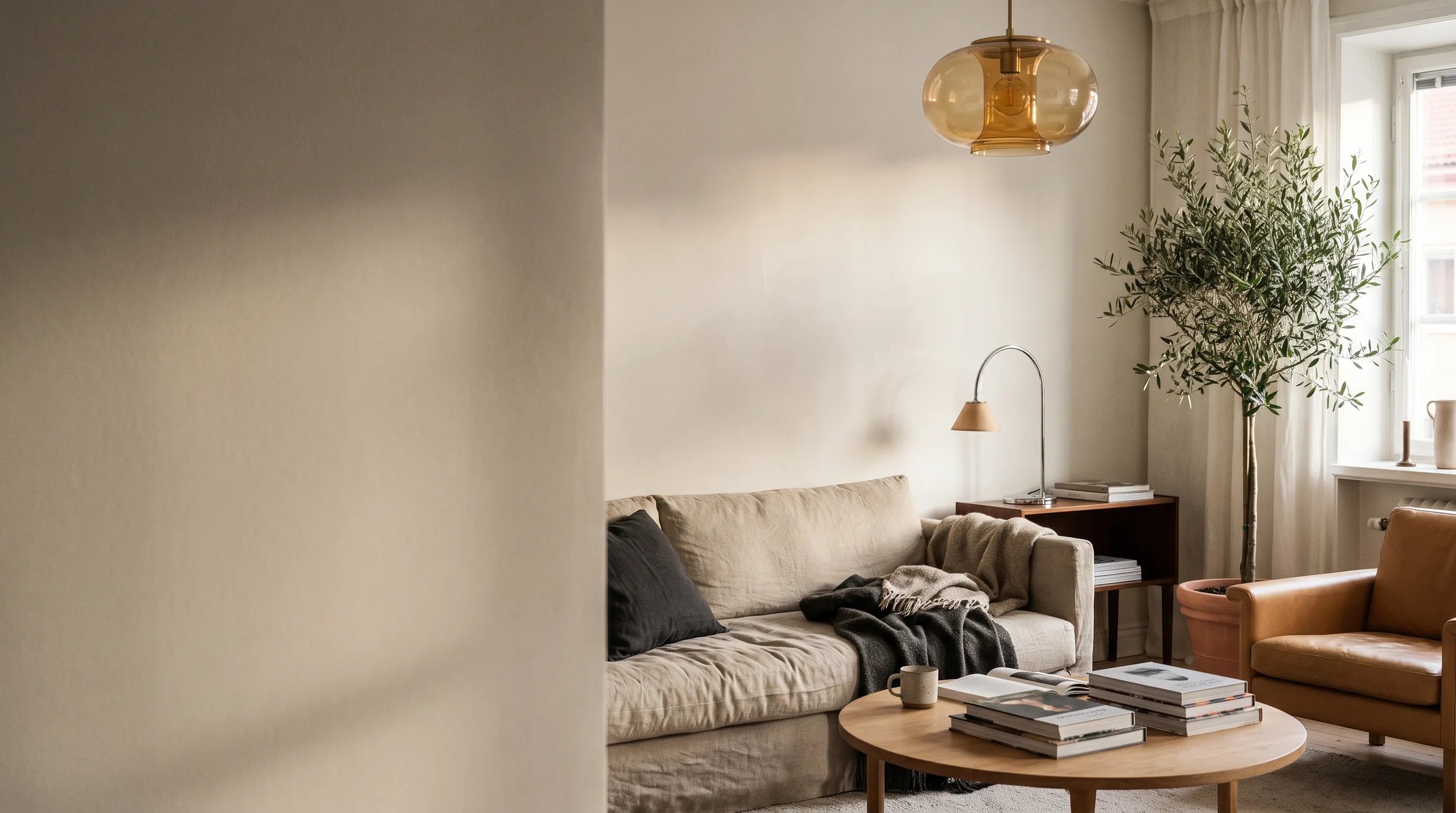 A warm living room lit by a glass pendant lamp at dusk